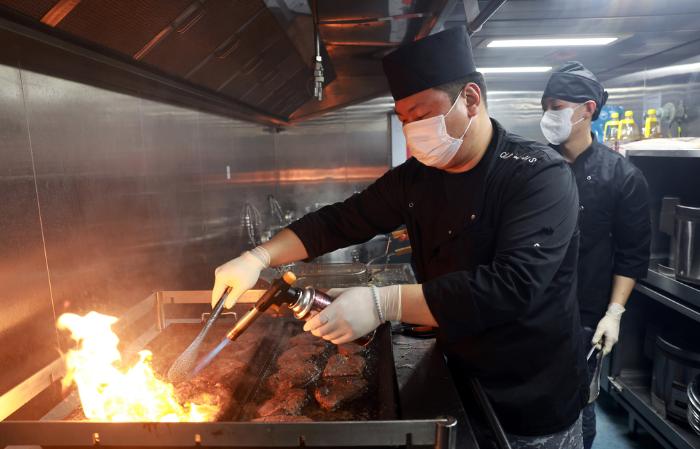 해군1함대 포항함 승조원 식당 주방에서 문효성(중사·왼쪽) 조리장이 토치를 활용해 부챗살 스테이크를 요리하고 있다.