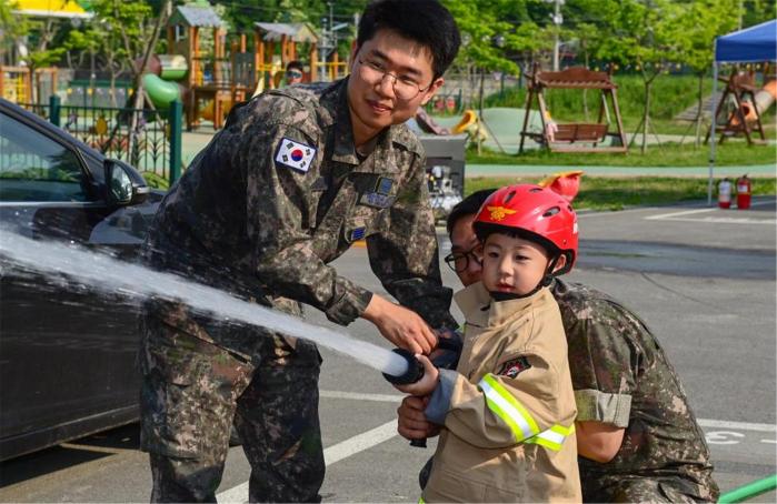 공군17전투비행단이 개최한 관사가족 화재예방교육에서 소방복을 입은 군 자녀가 화재 진압 체험을 하고 있다. 사진 제공=이호준 상사