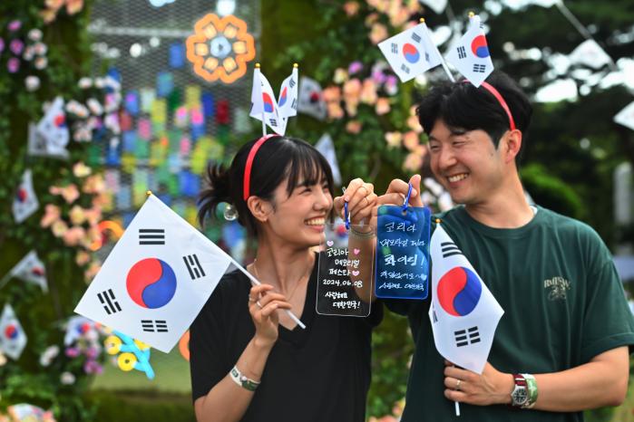 한 커플이 대한민국 영웅들을 위해 작성한 메시지를 들어 보이며 웃고 있다.