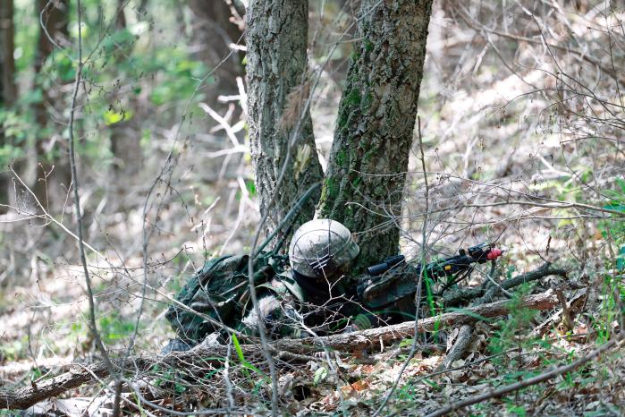 한 장병이 수풀에 몸을 숨긴 채 대항군을 수색하고 있다.