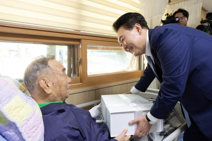 윤석열 대통령이 지난 21일 수원 보훈요양원에서 국가유공자에게 ‘영웅의 제복’을 선물하고 있다. 대통령실 제공