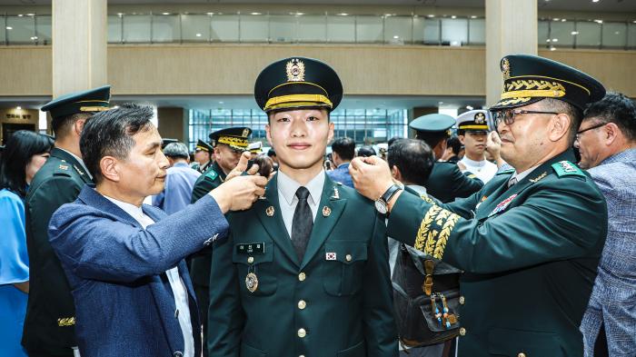 정진팔(오른쪽) 육군교육사령관과 군종사관 82기로 국방부장관상을 받은 이선재(가운데) 육군대위의 부모님이 이 대위의 어깨에 계급장을 달아주고 있다. 부대 제공