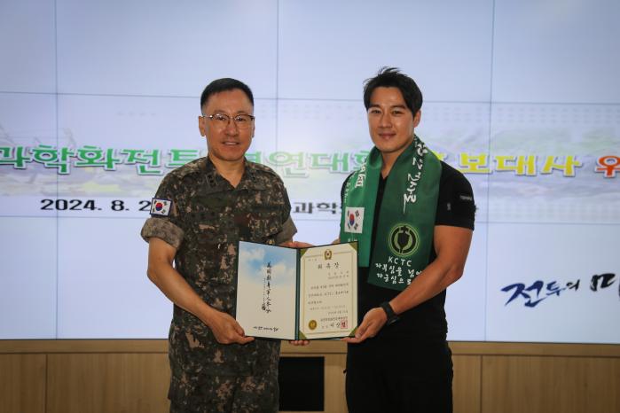 이상렬(왼쪽) 육군과학화전투훈련단장이 21일 열린 국제 과학화전투 경연대회(K-ICTC) 홍보대사 위촉식에서 최영재 씨에게 위촉장을 수여하고 있다. 부대 제공