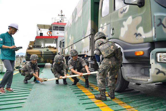 해군군수사 장병들이 27일 진해 군항에서 실시한 군 통제운영선박 동원훈련에서 5톤 윙바디 차량을 화물선에 결박하고 있다. 부대 제공