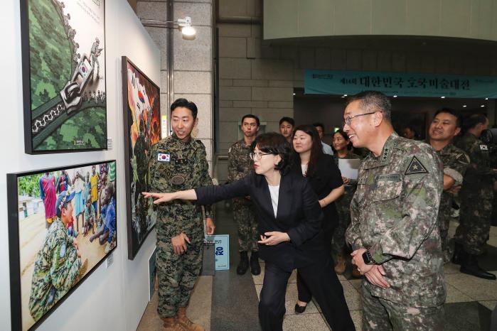 25일 서울 용산 전쟁기념관에서 열린 ‘제14회 대한민국 호국미술대전’ 개막식에서 고현석(오른쪽) 육군참모차장과 김선현(가운데) 대한임상미술치료학회장이 사진 부문 우수상 수상자인 박재선 소령(진)의 작품을 관람하고 있다.