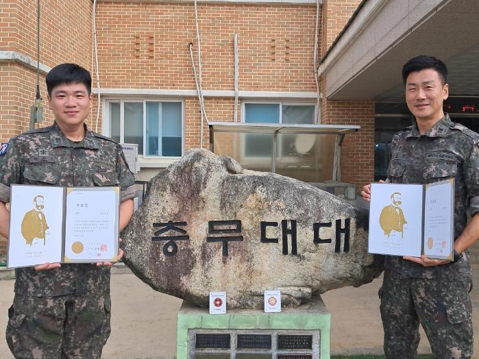 육군11기동사단 사자여단 오정환(오른쪽) 상사와 정진호 중사가 헌혈 100회 달성으로 수상한 대한적십자사 명예장을 들고 활짝 웃고 있다. 사진 제공=김민승 중위