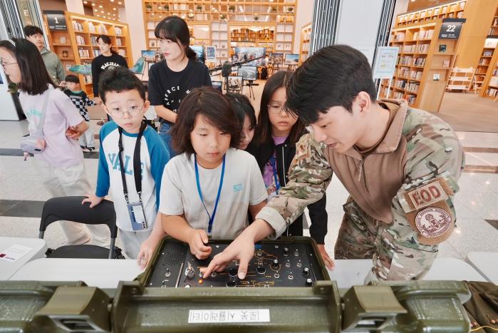 12일 국회부산도서관에서 열린 ‘국회부산도서관, 공군·항공과 함께하다’ 행사에서 폭발물처리반 장병이 어린이들에게 로봇 시뮬레이터 조종법을 알려주고 있다. 사진 제공=이요셉 소령