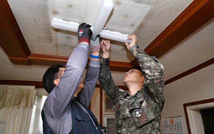 해군교육사령부 전기 교관과 한국전기안전공사 직원이 28일 지역 어르신 가정을 방문해 형광등을 LED 전등으로 교체하고 있다. 부대 제공