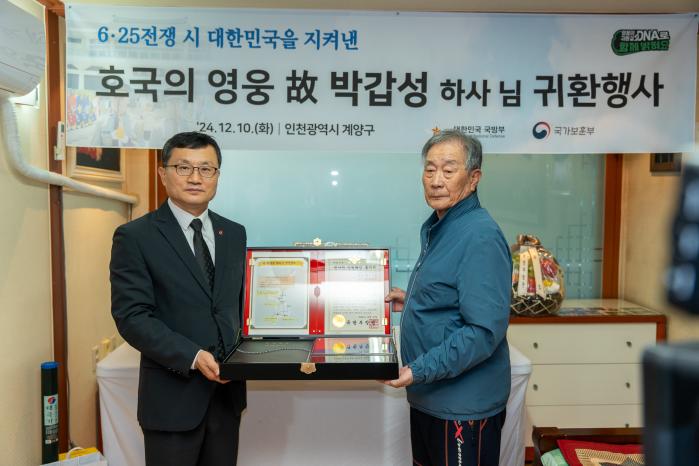 10일 인천시 계양구 고 박갑성 하사의 유가족 자택에서 진행된 ‘호국의 영웅 귀환행사’에서 이근원(왼쪽) 국방부 유해발굴감식단장이 유가족에게 ‘호국의 얼 함’을 전달하고 있다. 국유단 제공