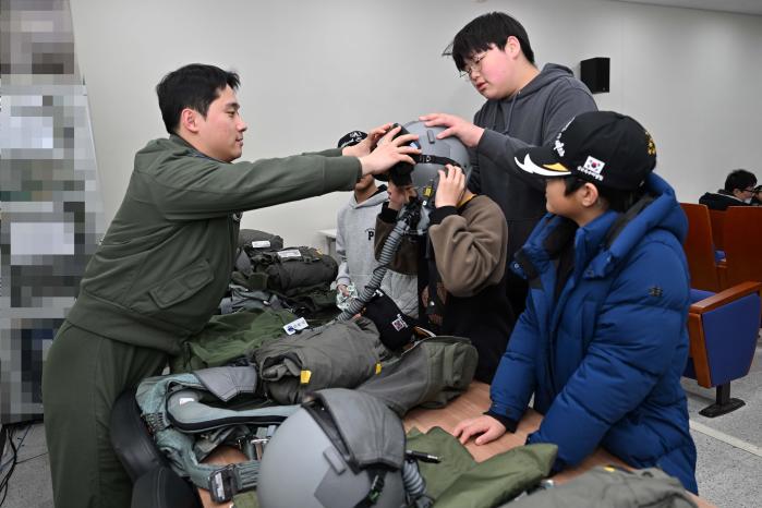 25일 공군8전투비행단을 방문한 한국항공우주소년단원들이 조종사의 도움을 받으며 헬멧을 착용하고 있다. 부대 제공