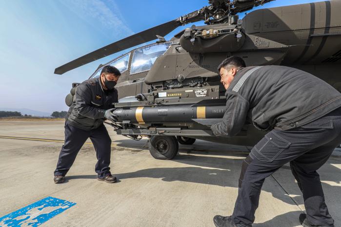 육군항공사령부 무장사들이 13일 AH-64E 아파치 공격헬기에 훈련용 헬파이어 공대지미사일을 장착하고 있다. 육군 제공