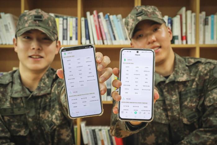 국군복지단 인터넷 쇼핑몰 ‘와몰’ 브랜드관을 이용하고 있는 군 장병들이 휴대전화를 들어보이고 있다. 부대 제공