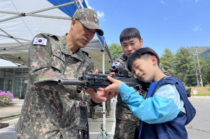 육군5군단이 개최한 가정의 달 행사에서 아이들이 간부의 도움을 받아 개인화기를 체험하고 있다. 부대 제공
