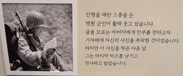 6· 25전쟁 당시 인형을 매단 소총을 든 군인이 글을 모르는 아버지에게 사진으로 안부를 전하는 모습. 하지만 이 사진을 찍은 다음 날 그는 전사했다.