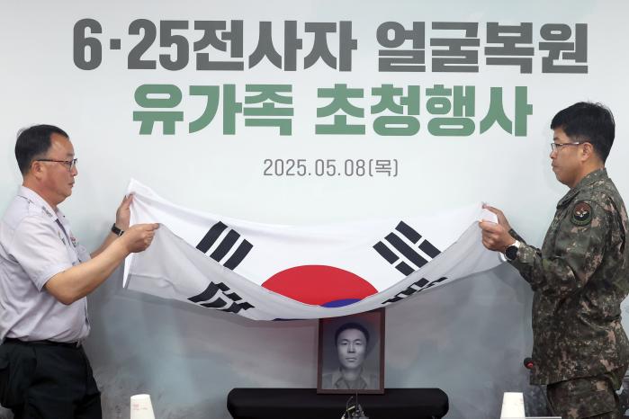 고 송영환 일병의 영정을 덮고 있던 태극기를 걷어 내는 국유단 관계자들.