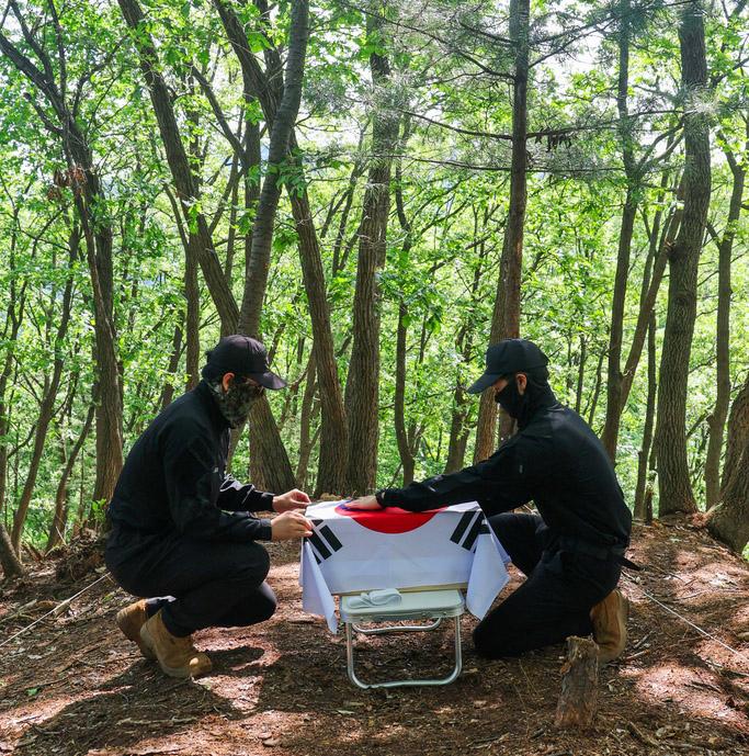 지난 22일 경기 가평군 외서면 상천리 340고지에서 국방부 유해발굴감식단 유해발굴팀이 현장에서 수습한 유해를 담은 오동나무 관을 태극기로 감싸고 있다.