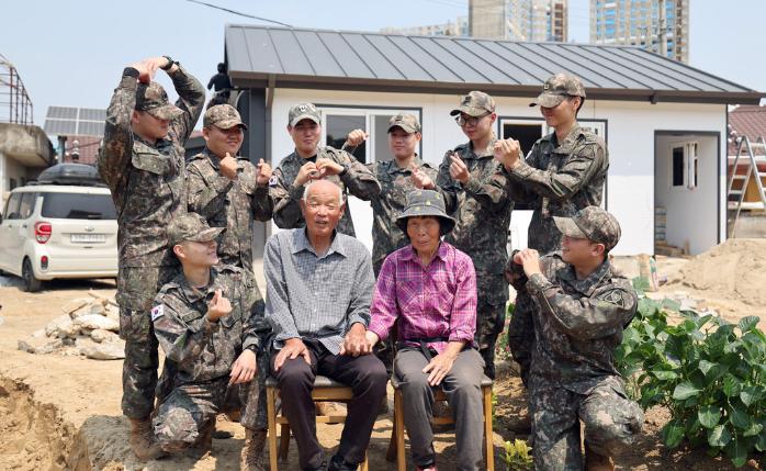 육군35보병사단 장병들이 지난달 29일 전북 익산시 함열읍 나라사랑 보금자리사업 현장에서 베트남전쟁 참전용사 임길춘 옹 부부와 함께 기념사진을 찍고 있다.