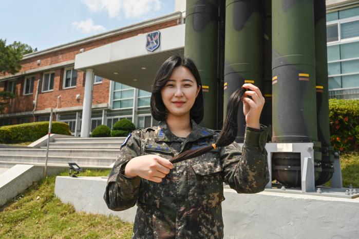 공군1미사일방어여단 강지수 예비역 대위가 전역 전 소아암 환우들을 위해 모발을 기부, 자른 머리카락을 들고 환하게 웃고 있다. 사진 제공=백진현 중사