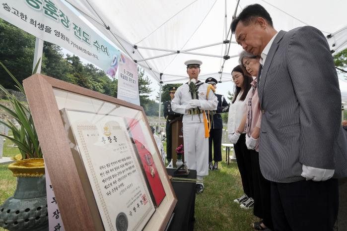 육군인사사령부 6·25무공훈장찾아주기조사단이 9일 국립서울현충원에서 거행한 고(故) 김진수 대위 무공훈장 전도수여식 중 김영철(맨 오른쪽) 씨를 비롯한 유가족이 66년 만에 고인의 묘역을 참배하고 있다. 그 옆으로 주인을 되찾은 금성화랑무공훈장과 훈장증이 보인다. 양동욱 기자