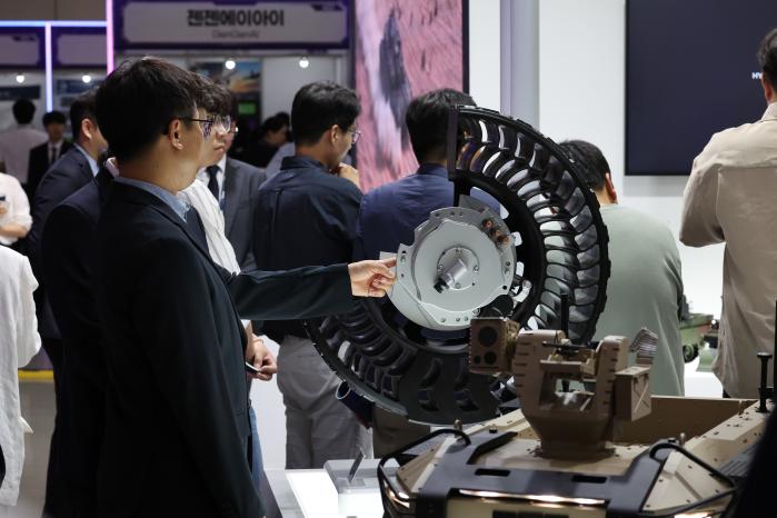 현대로템 부스에 전시된 인휠모터를 살펴보는 관람객 및 관계자.