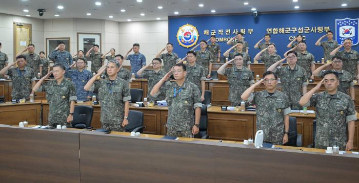 15일 해군작전사령부 대형 화상회의실에서 열린 전반기 교육훈련 분석평가회의에서 황선우(앞줄 가운데) 사령관을 비롯한 참석자들이 국기에 대한 경례를 하고 있다. 부대 제공