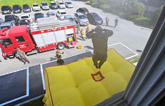 공군1전비가 지난 25일 진행한 건물 화재 진압훈련에서 구조자가 에어매트로 뛰어내리고 있다. 사진 제공=장석원 중사