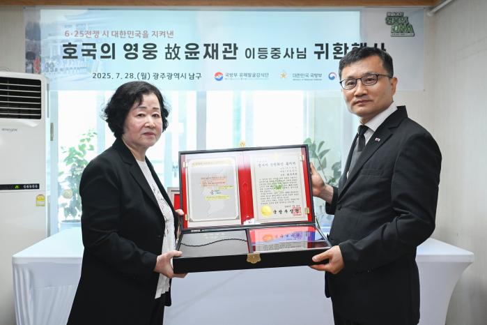 이근원(오른쪽) 국방부유해발굴감식단장이 28일 고 윤재관 이등중사의 유가족 윤금순 씨에게 ‘호국의 얼 함’을 전달하고 있다. 부대 제공