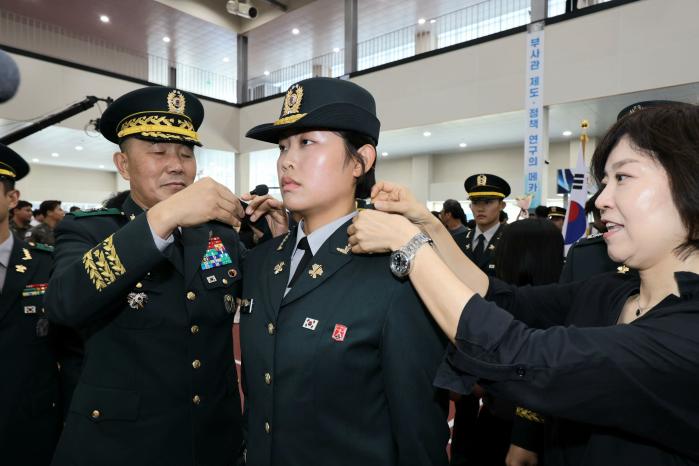 김진철(맨 왼쪽) 육군교육사령관 직무대리가 임관자 대표 조현비 하사에게 계급장을 달아 주고 있다.