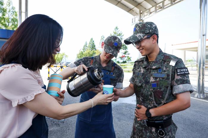 이선희(맨 왼쪽) 군무주무관과 커피 동아리 장병들이 위병소 근무자에게 시원한 아이스아메리카노를 전달하고 있다.