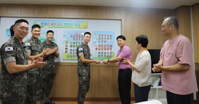 육군훈련소 고하영(가운데) 중사가 육군 인권 콘텐츠 공모전에서 받은 상금을 논산 연무초등학교에 전달하고 있다. 부대 제공