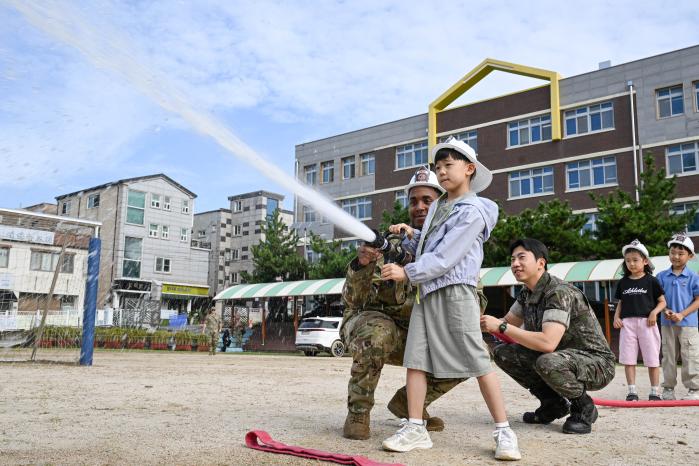 29일 공군38전투비행전대와 미공군8전투비행단 소방구조대원들이 군산지곡초등학교 학생들에게 소방 호스 사용법을 가르쳐주고 있다. 사진 제공=정미강 상병