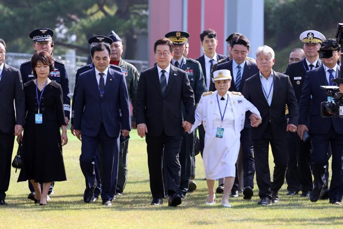 이재명 대통령이 국민대표로 참석한 6·25전쟁 참전유공자 이종선(가운데) 여사의 손을 잡고 행사장에 입장하고 있다.