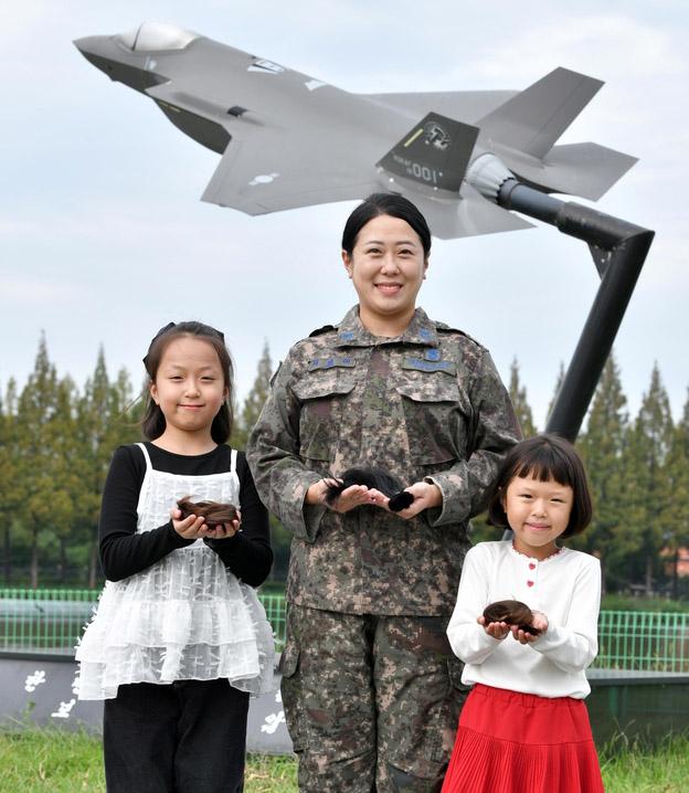 공군17전투비행단 항공기정비대대 서승이 중사가 딸들과 함께 어린 암 환자들에게 기부할 머리카락을 들어 보이고 있다.