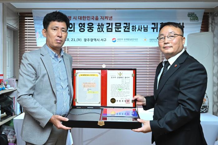 조해학(오른쪽) 국방부 유해발굴감식단장 직무대리가 21일 고 김문권 하사 유가족 대표인 친조카 김대중 씨에게 호국의 얼 함을 전달하고 있다. 부대 제공