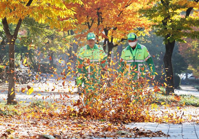 5일 경기 수원시 팔달구 수원제1야외음악당 주변 인도에서 수원시청 환경관리원들이 낙엽을 전동송풍기로 청소하고 있다. 연합뉴스