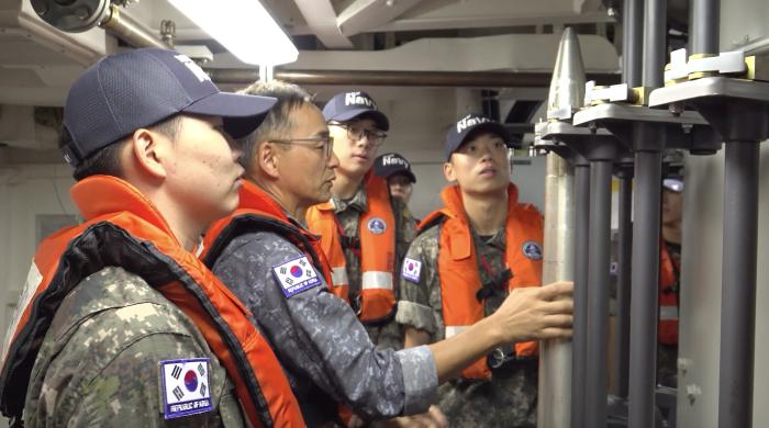 생도들이 함 승조원으로부터 함포 탄약 장전 절차를 듣고 있다.