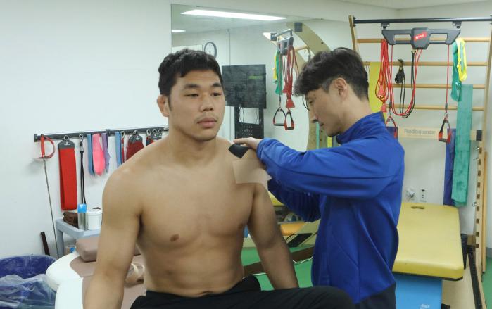 국군체육부대 국군전투체력개발센터 박해찬 스포츠의학담당이 스포츠의학실에서 레슬링 이경연 상병에게 테이핑을 하고 있다.