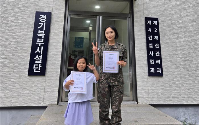 국방시설본부 경기북부시설단 이상미(오른쪽) 육군중사와 딸 전아리 양이 모발기부증서를 들어 보이고 있다. 부대 제공