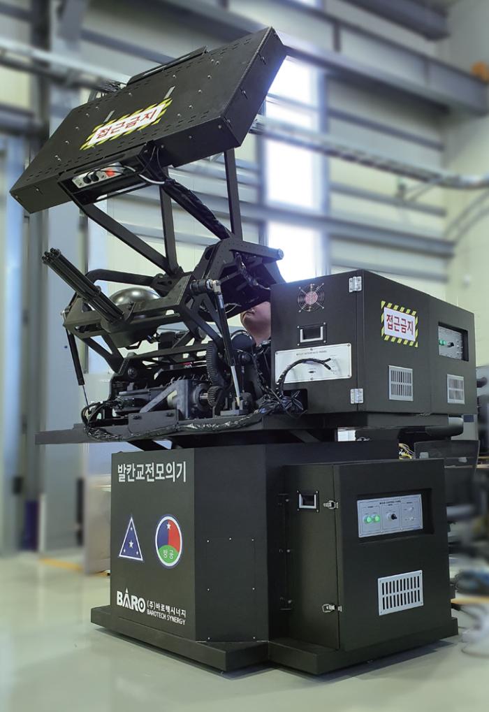 바로텍시너지가 생산하고 있는 발칸교전모의기는 실제 장비와 동일한 크기와 조작 체계, 방위각·고각 독립 모션을 구현한 고성능 시뮬레이터다.