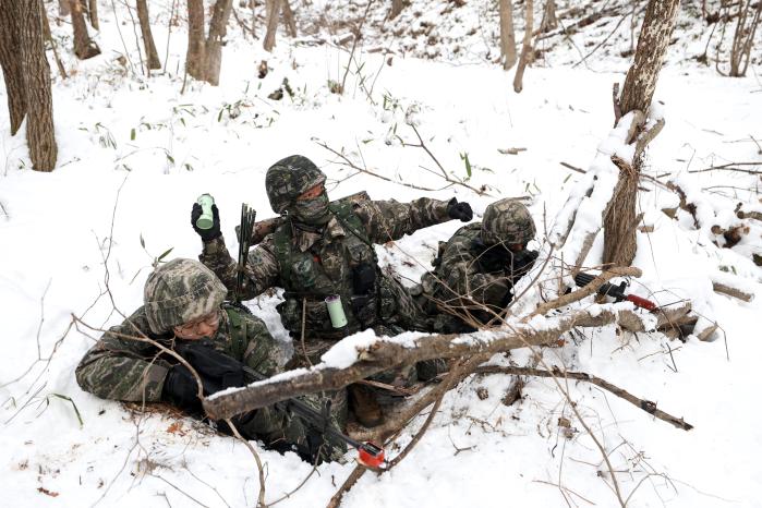 방어 임무를 맡은 장병이 전우의 엄호를 받으며 연막탄을 던지고 있다.