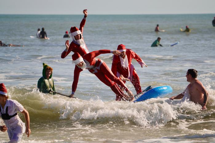 24일(현지시간) 플로리다주 코코아비치에서 산타 복장을 한 사람들이 서핑을 하고 있다. AP·연합뉴스