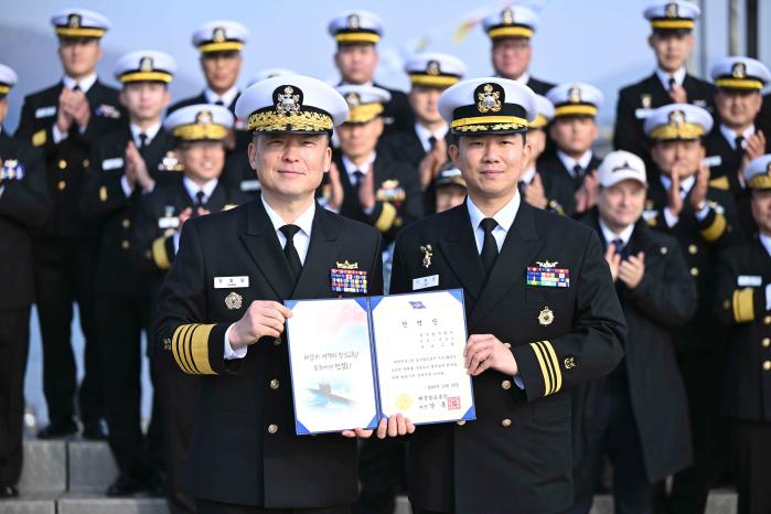 강동길(왼쪽) 해군참모총장과 이제권 장보고함장이 명예전역장을 들어 보이고 있다. 해군 제공