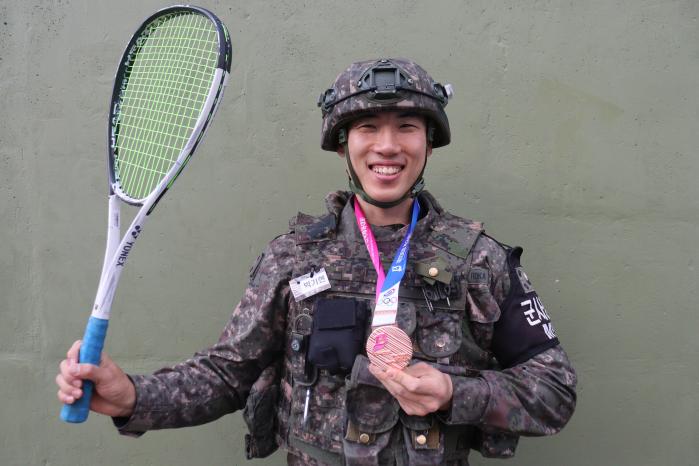 육군22보병사단 건봉산대대 박기현 상병이 전국체전에서 수상한 동메달과 소프트테니스 라켓을 들고 환하게 웃고 있다. 사진 제공=송영빈 소위