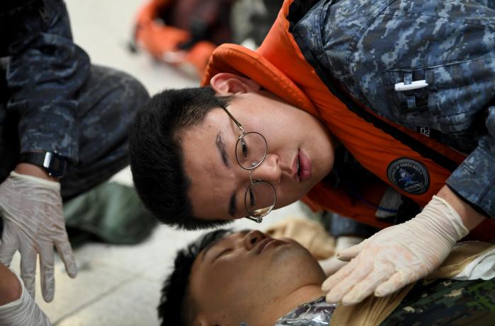 부상자의 호흡을 확인하는 장병.