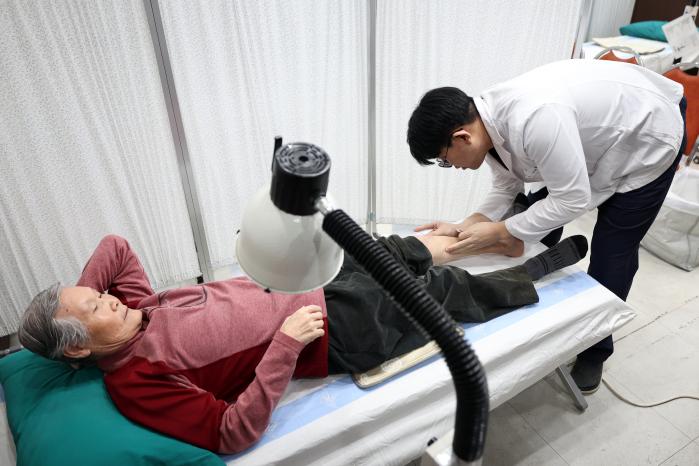 의무대대 군의관이 마을 주민에게 침을 놓고 있다.