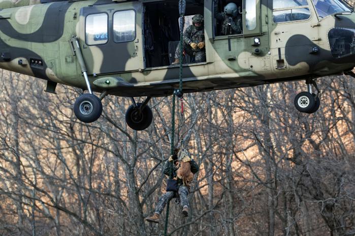 육군35보병사단이 20일 혹한기 전술훈련의 하나로 전개한 급속 헬기 로프 하강 훈련에서 육군교육사 군견훈련소 2군견지원대 유지산 작전팀장이 군견 ‘사자’와 함께 하강하고 있다.