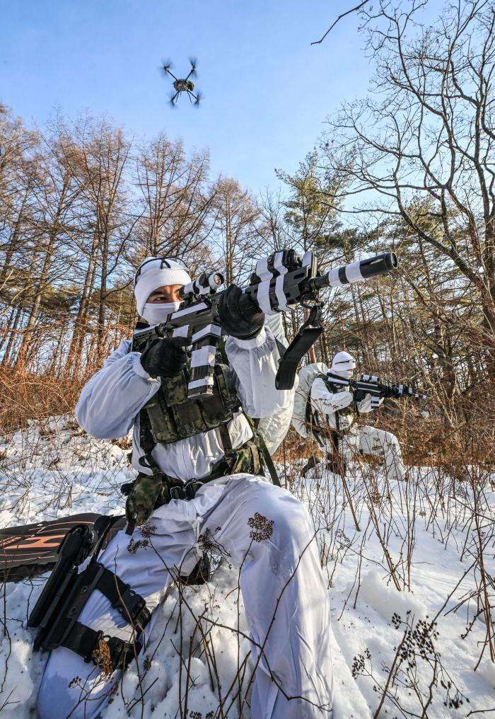 육군특수전사령부 비호부대 특전대원이 설한지 극복훈련 중 적 후방에 침투해 드론과 함께 정찰하고 있다.