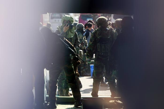 육군53보병사단 울산여단 장병들이 지난 12일 울산대공원 일대에서 열린 대량사상자 관리훈련에서 인체제독소에 입장하기 위해 오염된 장구류를 제거하고 있다.