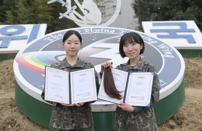 공군3훈련비행단 최서윤(왼쪽) 중위와 전미화 상사가 모발기부 증서와 머리카락을 들어 보이고 있다.