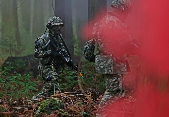 붉은 연막이 피어오른 숲 사이로 장병들이 기동하고 있다.